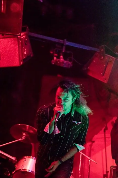 Singer on stage with a microphone, lit in red and green
